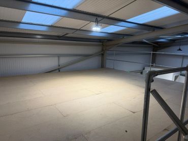 Empty industrial mezzanine floor with metal railings and overhead lighting.