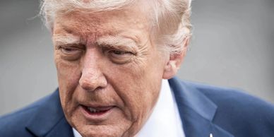 Close-up of a serious man with light hair and a suit.