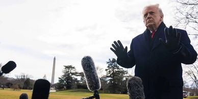 A man speaking to reporters outdoors with microphones.