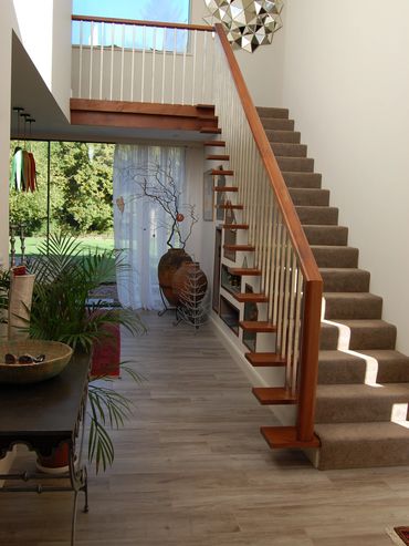 Modern staircase with wooden accents and carpeted steps in a bright home.