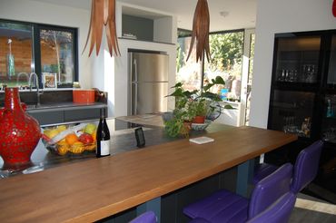 Modern kitchen with wooden countertop and purple chairs.