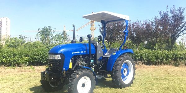 Blue Jinma 404C tractor parked on grassy field under clear sky.