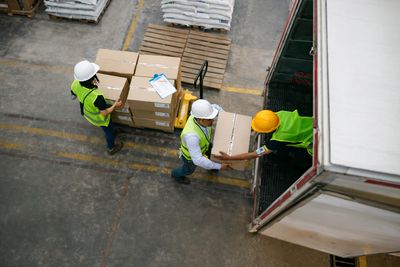 Workers in safety gear loading boxes into a truck.
