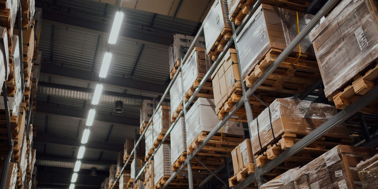 Warehouse shelves stacked with pallets of boxed goods wrapped in plastic.