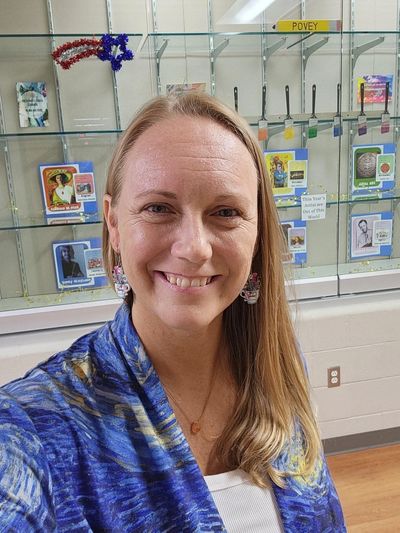 Smiling woman in blue patterned shawl taking a selfie indoors.