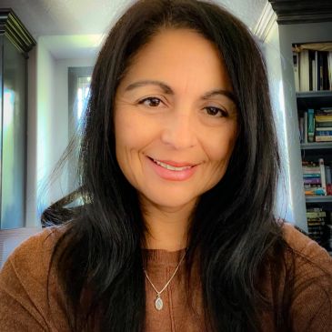 Smiling woman with long dark hair indoors.