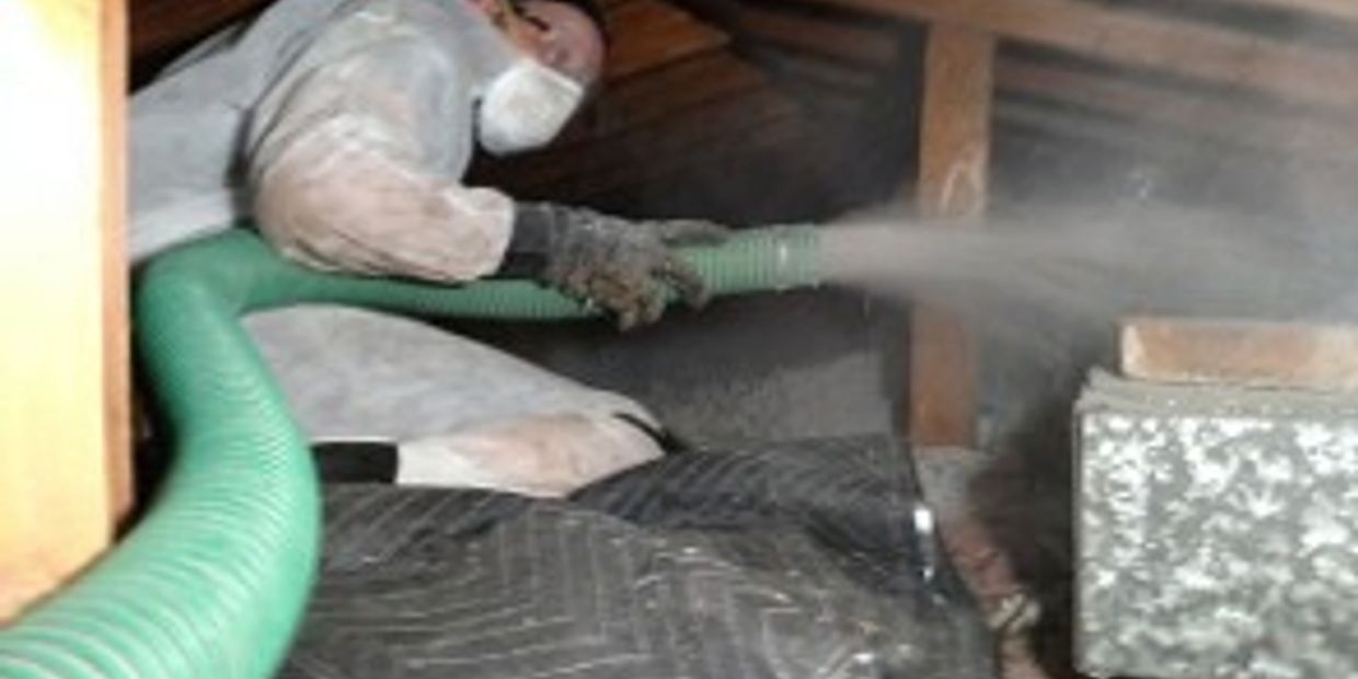 A tech blowing in insulation into an attic