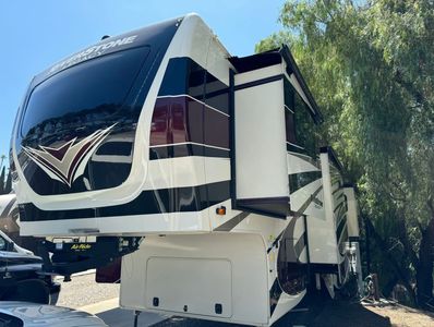Large Riverstone Legacy fifth-wheel RV parked with slide-outs extended under clear sky.