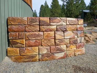 Stone wall with rectangular blocks near a building.