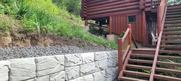 Stone retaining wall by a wooden staircase.