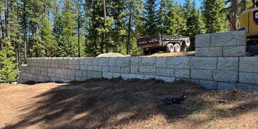 A newly built stone retaining wall in a forest area.