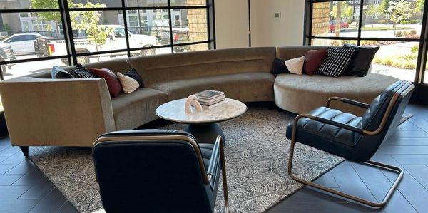 Modern living room with a curved sofa and black armchairs around a marble coffee table.