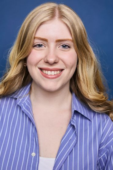 Smiling young woman with blonde hair and blue striped shirt.