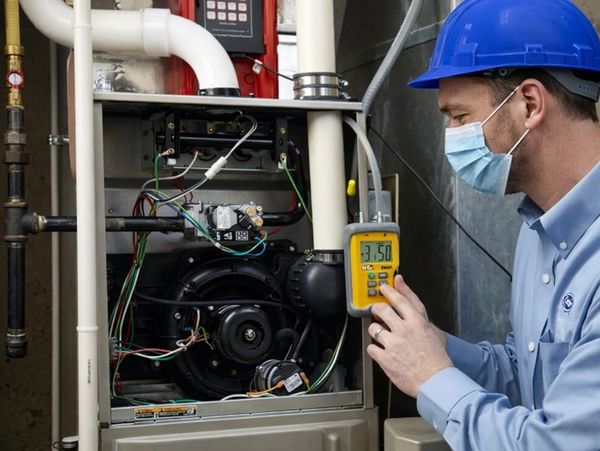 A technician using a digital testing tool on a home furnace. Trusted Heating Repair in Woodbury to r