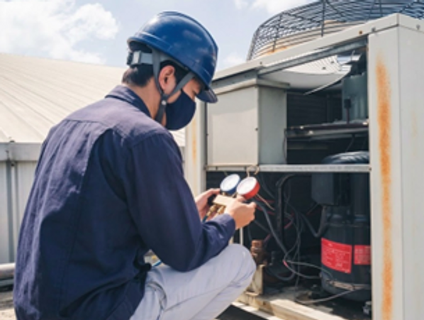 An HVAC technician checking gauges on a large outdoor unit. Trusted Heating Repair in Forest Lake by