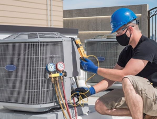 HVAC technician performing HVAC repair in Fridley by checking AC unit pressure with gauges and tools