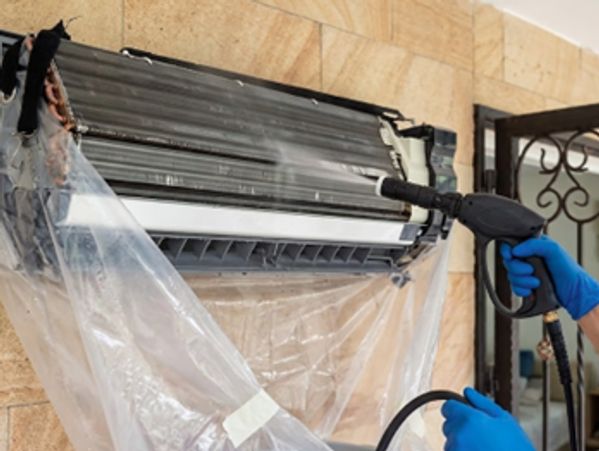 Technician performing AC Repair in Ramsey by cleaning indoor AC unit with pressure washer for effici