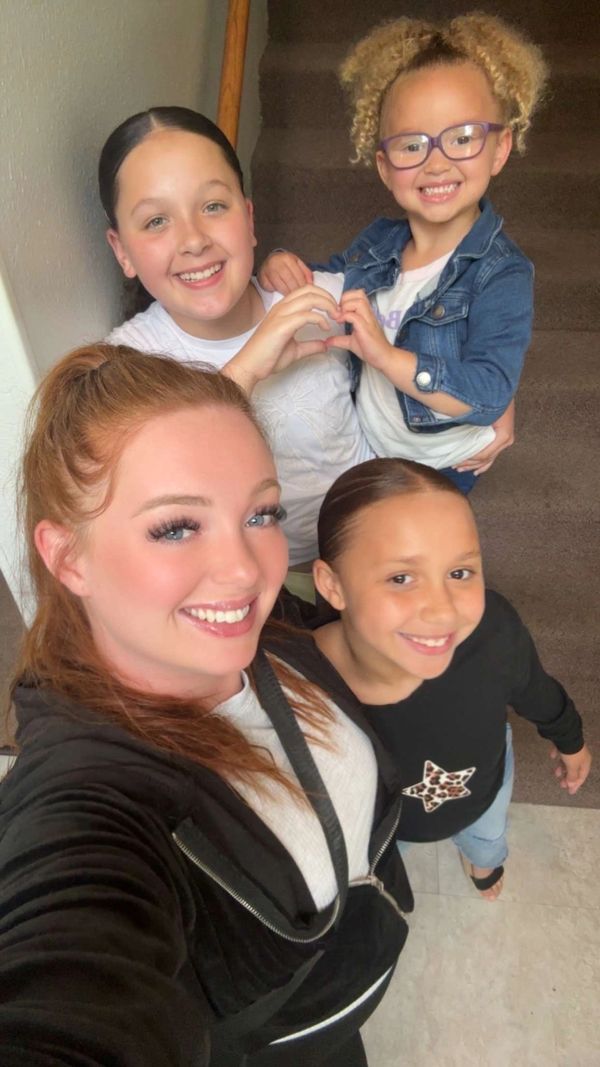 Four smiling girls taking a happy selfie indoors.