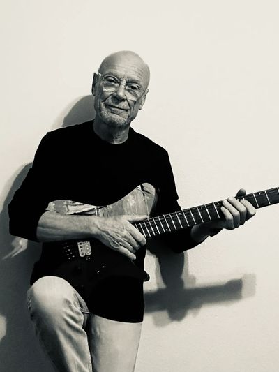 Elderly man playing an electric guitar, captured in black and white.