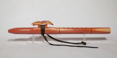 Wooden Native American-style flute with a decorative bird and leather strap.