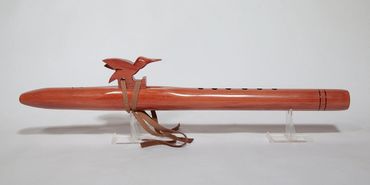 Wooden flute with bird decoration and leather strap.
