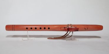 Traditional wooden flute with multiple finger holes and leather straps.