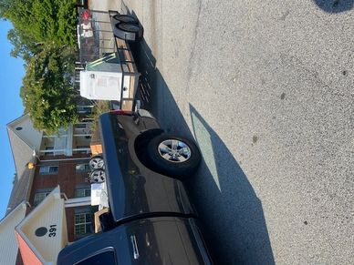 A black pickup truck towing a trailer with appliances in a residential area.