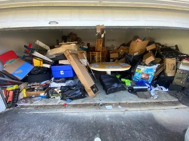 A cluttered garage filled with boxes, furniture, and miscellaneous items.