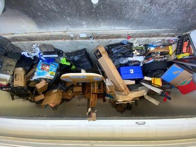 A cluttered garage filled with boxes, furniture, and miscellaneous items.