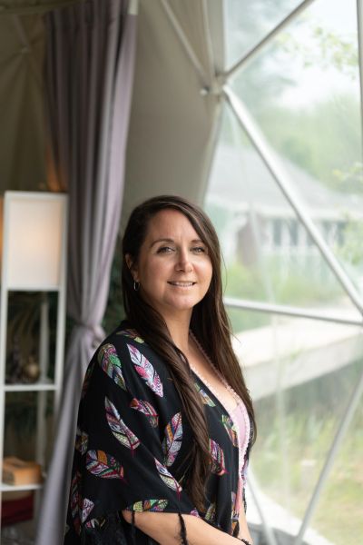 A woman smiling near a large window indoors.