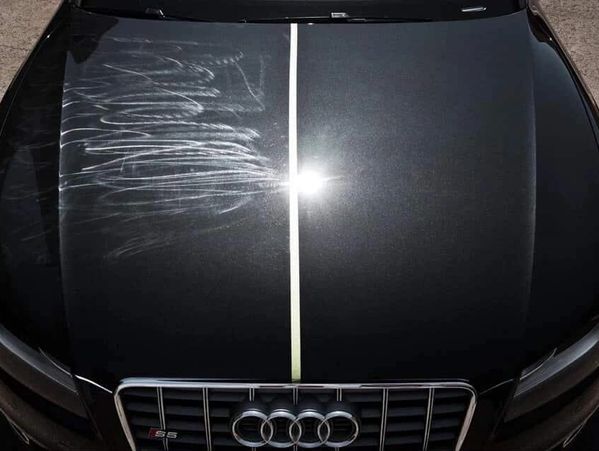 Car hood showing a clear difference between scratched and polished surfaces.