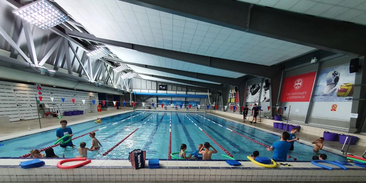 Evolution Swim School swimming lesson in Edinburgh with a teacher supporting children in the pool.