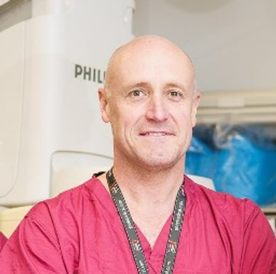 A medical professional in red scrubs stands confidently in a clinical setting.