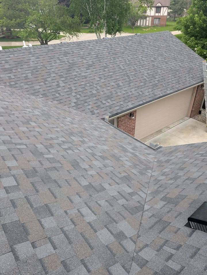 Newly installed gray and brown asphalt shingle roof on a residential home.
