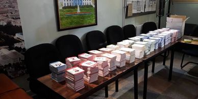 Stacks of cards or booklets arranged on a long table in a room with chairs.