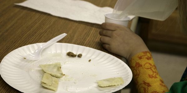 A child pouring a drink while working on self feeding and improving resistant eating in OT.