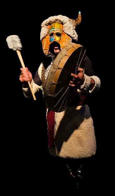 Person in traditional costume playing a drum.