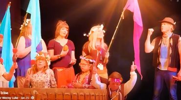 Group in colorful tribal costumes performing on stage.