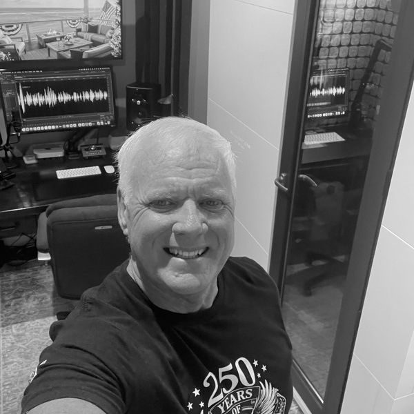 Smiling man taking a selfie in a room with audio equipment.