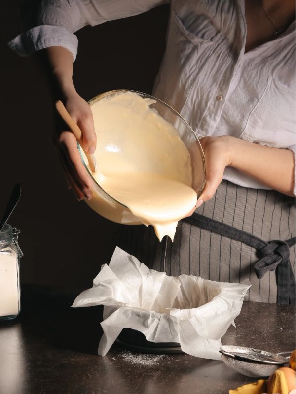 Pouring batter into a lined baking pan.