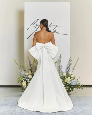Back view of a white strapless gown with a large bow.