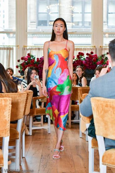 Model walking on runway in a colorful dress.