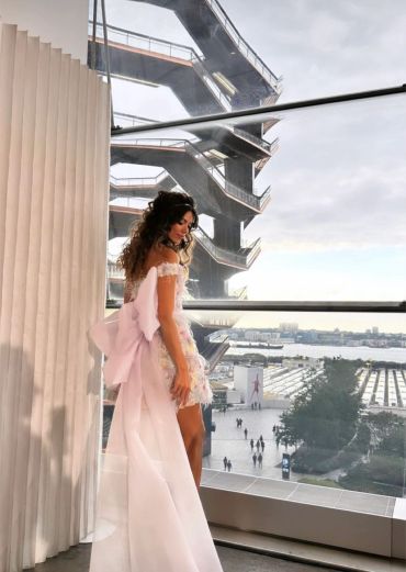 Woman in elegant dress looking out at city view.