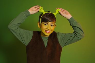 Child dressed as Shrek with green ears and brown vest.