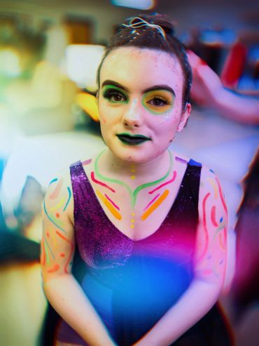 Person with colorful face and body paint looking up.