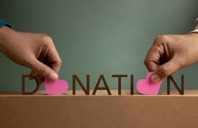 Hands placing heart shapes on the word 'DONATION' symbolizing charity.