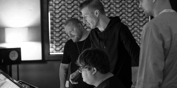 Four men working together in a recording studio.