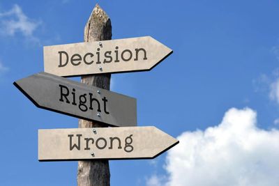 Signpost showing directions labeled Decision, Right, and Wrong against a blue sky.