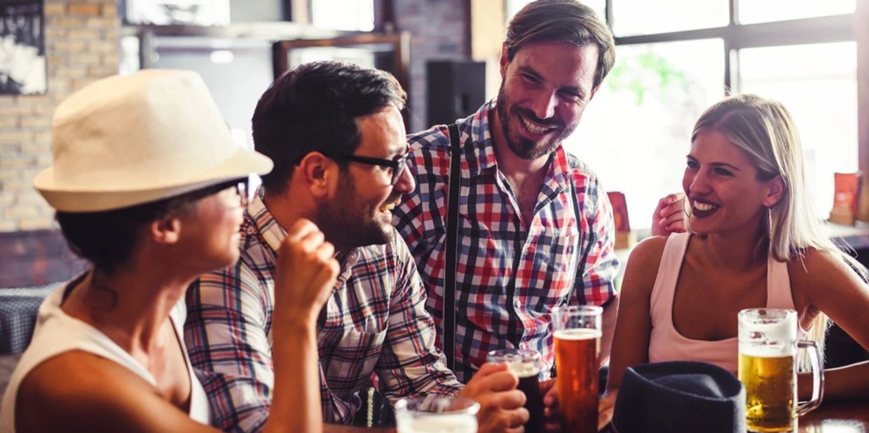 Happy friends having fun at bar - Young trendy people drinking beer and laughing together