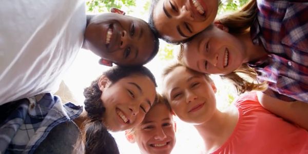 6 kids in a circle hugging with a picture of them from below looking up towards their smiles.